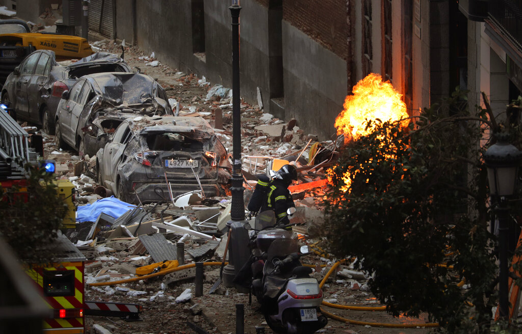 Bomberos trabajan para sofocar un incendio junto a un edificio dañado por una explosión en el centro de Madrid, el miércoles 20 de enero de 2021. (AP)