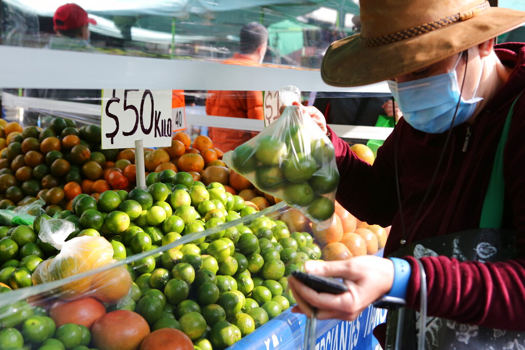 Un comprador sostiene una bolsa de limones en un puesto de mercado en la Ciudad de México, México, el 16 de enero de 2022. (AP)